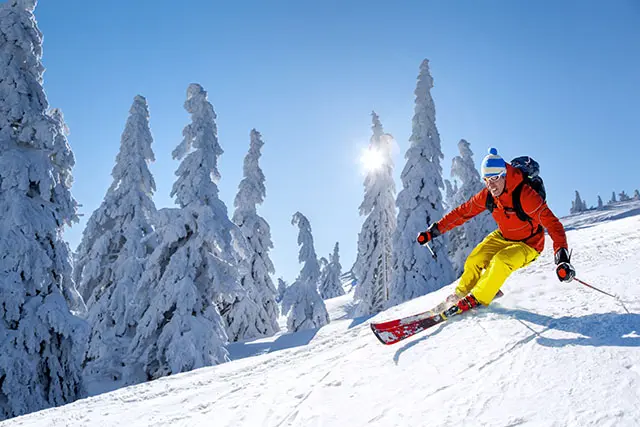 Skier skiing downhill in high mountains against blue sky