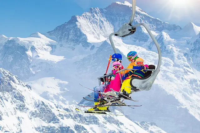 Family in ski lift in mountains. Skiing with kids