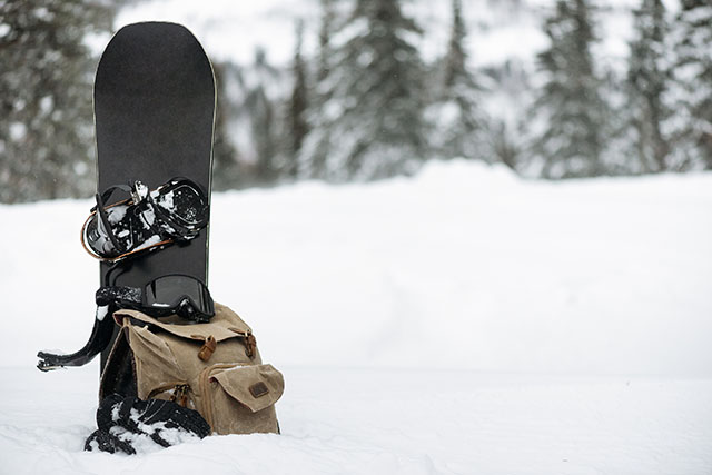 Snowboard, snowboard goggles and backpack on the snow. Snowboard